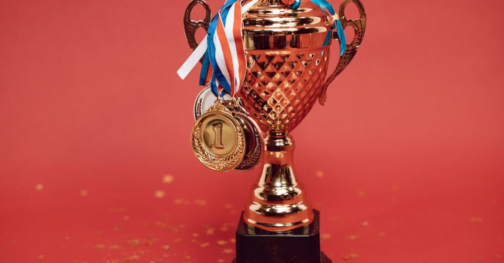 Golden trophy adorned with medals on a red backdrop surrounded by scattered confetti.